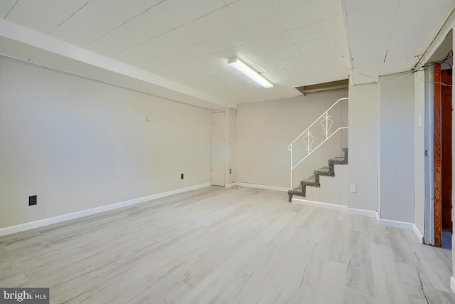 finished below grade area with stairs, baseboards, and light wood-type flooring