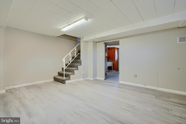 finished basement with stairway, baseboards, visible vents, and wood finished floors