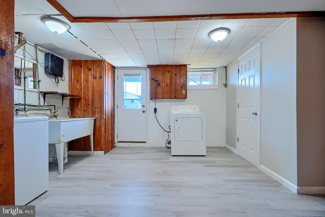 laundry room featuring light wood-style flooring, washer / clothes dryer, cabinet space, and baseboards