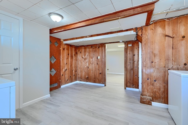 finished basement with wooden walls, washer / clothes dryer, and wood finished floors