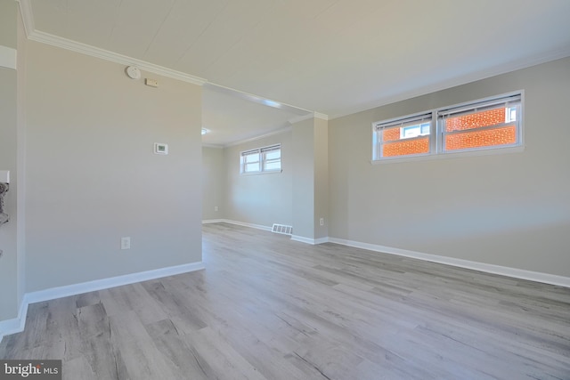 spare room with visible vents, wood finished floors, baseboards, and ornamental molding