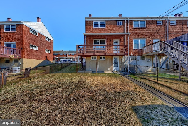 rear view of house with brick siding, stairway, a lawn, and a fenced backyard