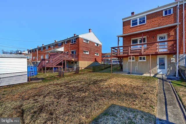 back of house featuring fence, brick siding, and a lawn