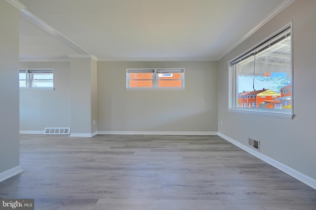 unfurnished room with crown molding, wood finished floors, visible vents, and baseboards