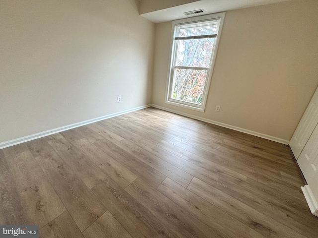 empty room featuring visible vents, baseboards, and wood finished floors