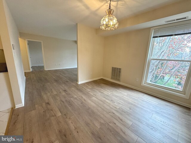 unfurnished dining area with a wealth of natural light, visible vents, and wood finished floors