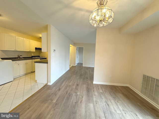 kitchen with visible vents, light wood finished floors, an inviting chandelier, white gas stove, and dark countertops