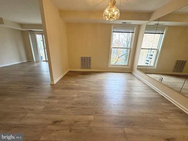 unfurnished dining area with visible vents, a healthy amount of sunlight, and wood finished floors