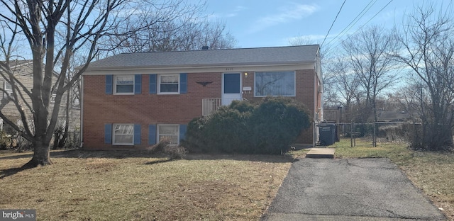 view of front of home with a gate, brick siding, a front yard, and fence