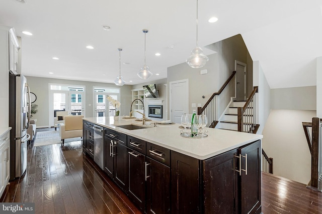 kitchen featuring open floor plan, light countertops, dark wood-style floors, stainless steel appliances, and a sink