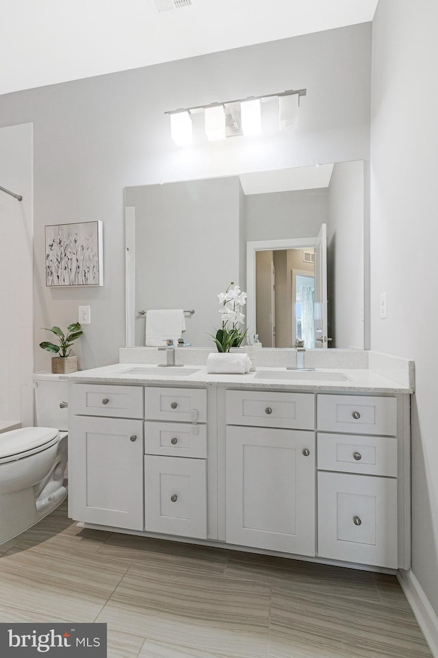 bathroom featuring double vanity, toilet, and a sink