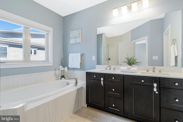 bathroom featuring a bath, a stall shower, double vanity, and a sink