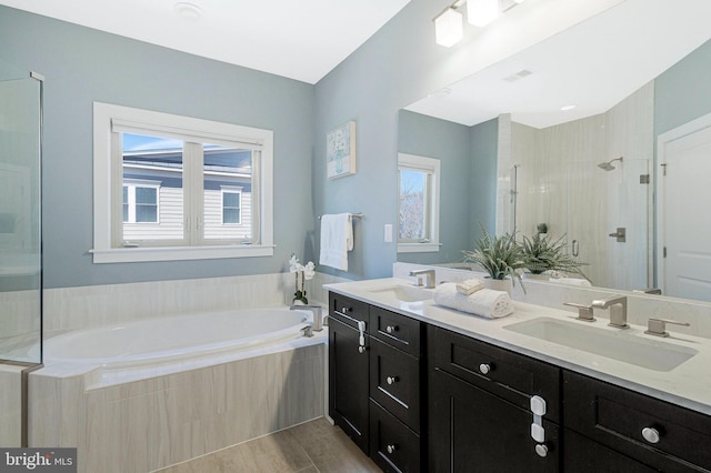 bathroom with double vanity, a stall shower, a garden tub, and a sink