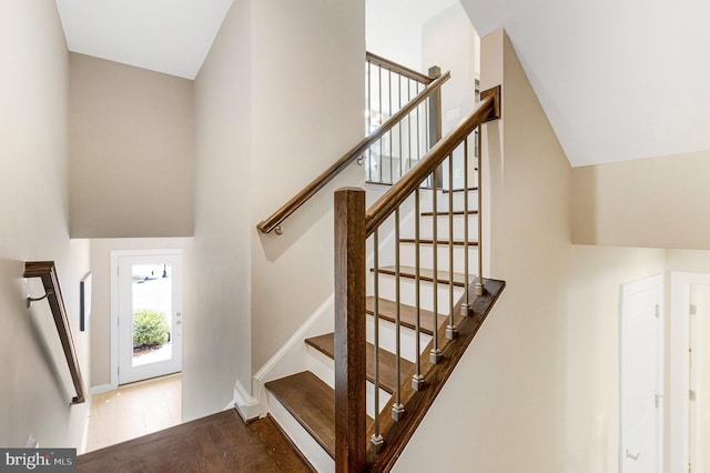 stairway featuring baseboards and high vaulted ceiling