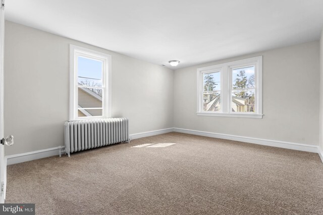 empty room featuring baseboards, carpet, and radiator heating unit