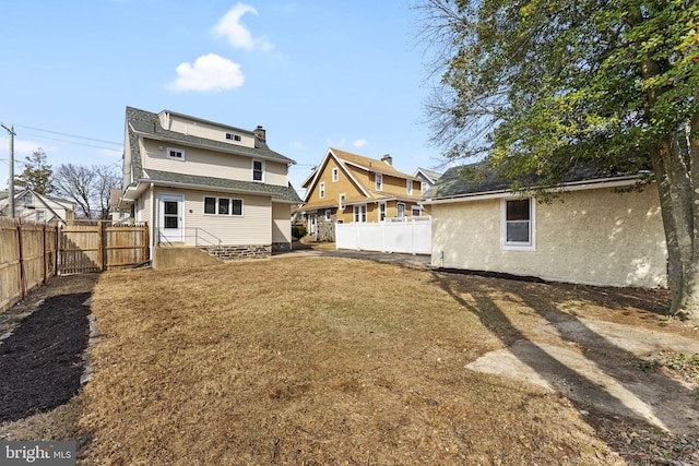 rear view of house with a lawn, a fenced backyard, and entry steps