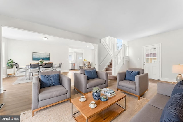 living area with light wood finished floors, visible vents, stairs, and baseboards