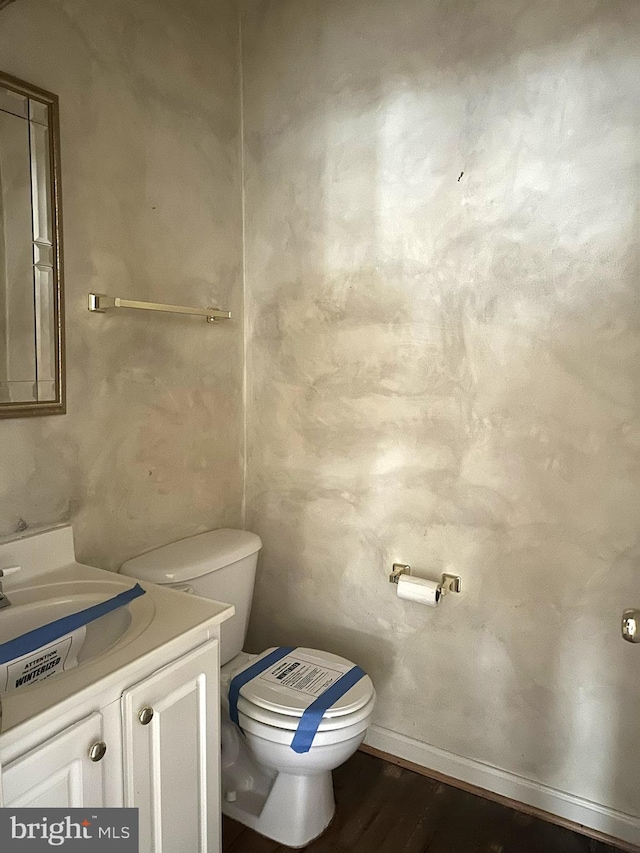 bathroom with baseboards, toilet, wood finished floors, and vanity