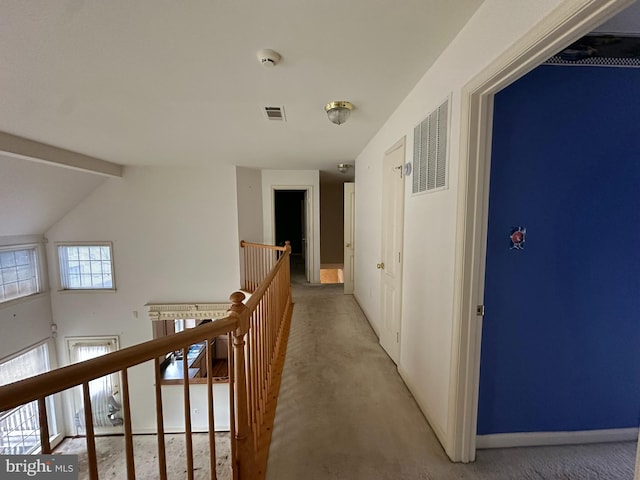 hall with visible vents, an upstairs landing, light colored carpet, and baseboards