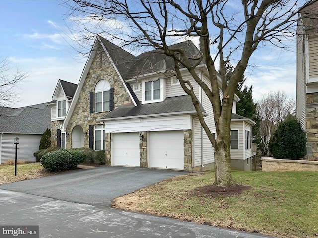 view of front of home featuring a garage, stone siding, and driveway