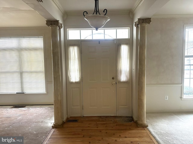 entryway featuring plenty of natural light, ornate columns, and ornamental molding