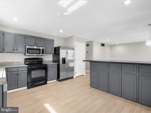 kitchen with a textured ceiling, appliances with stainless steel finishes, light wood-style flooring, and gray cabinets