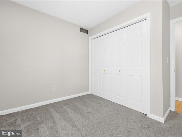 unfurnished bedroom with visible vents, carpet floors, baseboards, and a closet