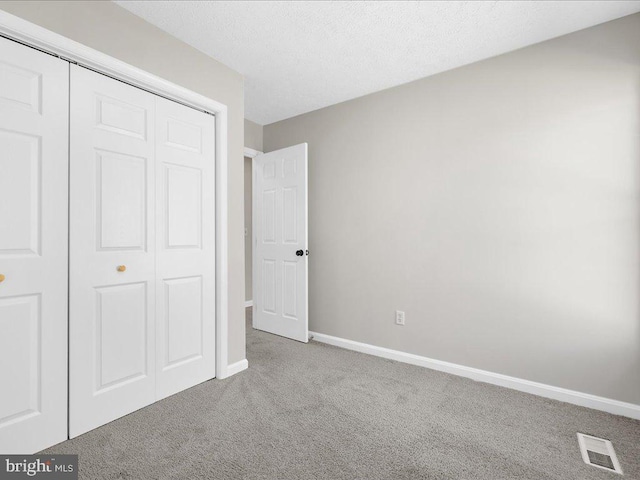 unfurnished bedroom with visible vents, baseboards, carpet flooring, a closet, and a textured ceiling