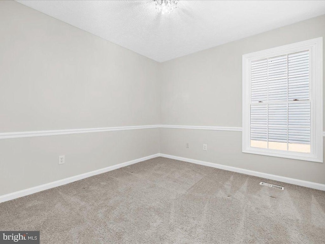 spare room featuring visible vents, a textured ceiling, baseboards, and carpet floors