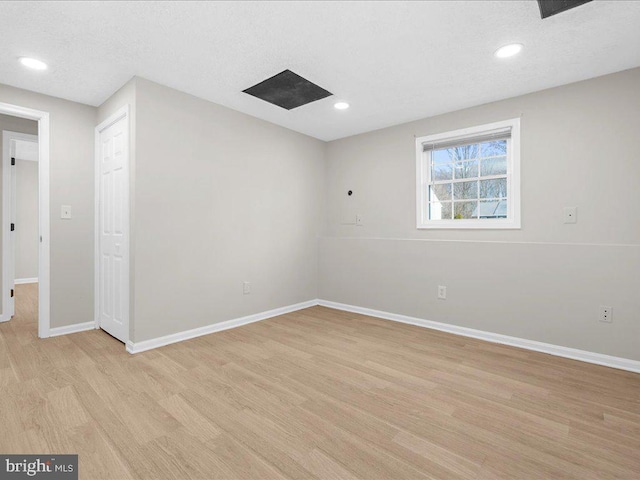 empty room featuring recessed lighting, baseboards, a textured ceiling, and light wood finished floors