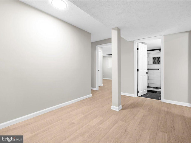 interior space featuring light wood-style flooring, a textured ceiling, and baseboards