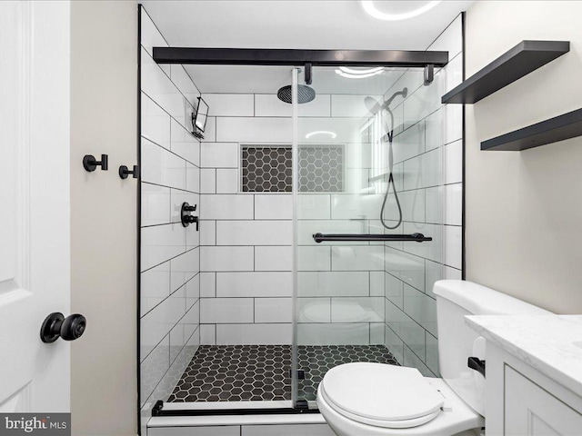 bathroom with a stall shower, toilet, and vanity