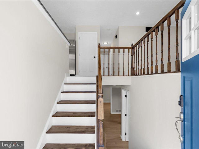 stairs with recessed lighting, wood finished floors, and baseboards