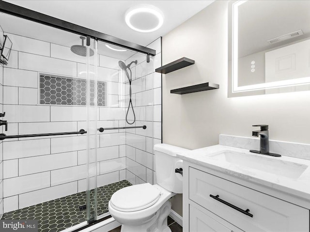 bathroom with vanity, toilet, visible vents, and a stall shower