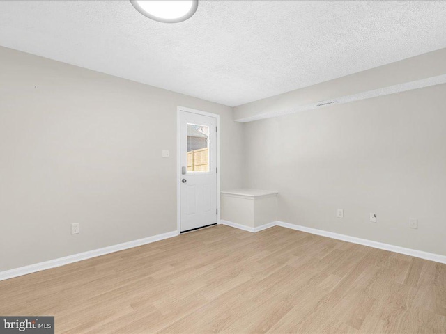 unfurnished room with baseboards, a textured ceiling, and light wood finished floors