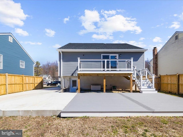 rear view of property with a deck, a patio, stairway, and fence