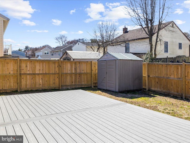 deck with a storage unit, a residential view, an outdoor structure, and a fenced backyard