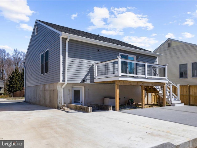 back of property featuring fence, stairway, concrete driveway, stucco siding, and a deck