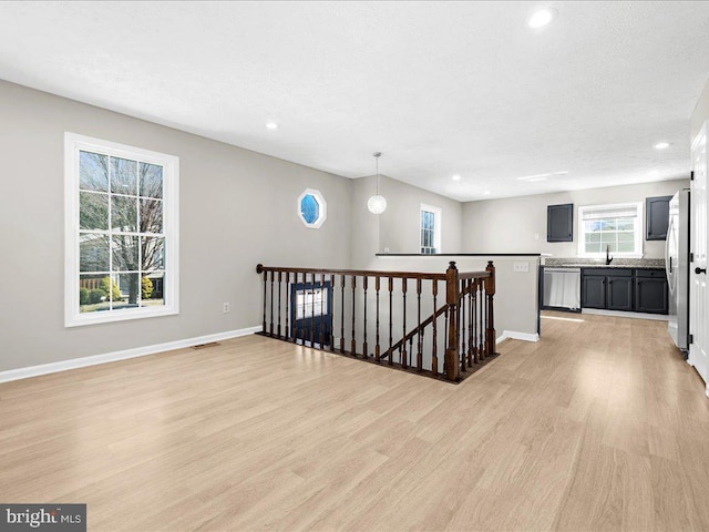 hallway with light wood finished floors, baseboards, an upstairs landing, recessed lighting, and a sink