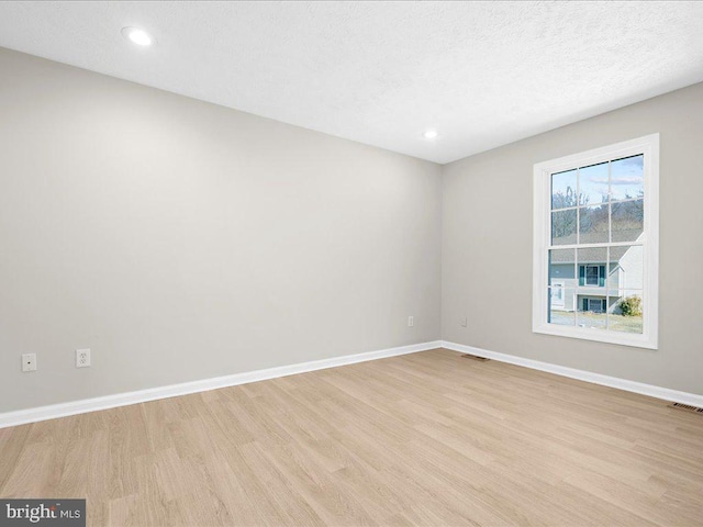 empty room featuring light wood-style flooring, baseboards, and visible vents