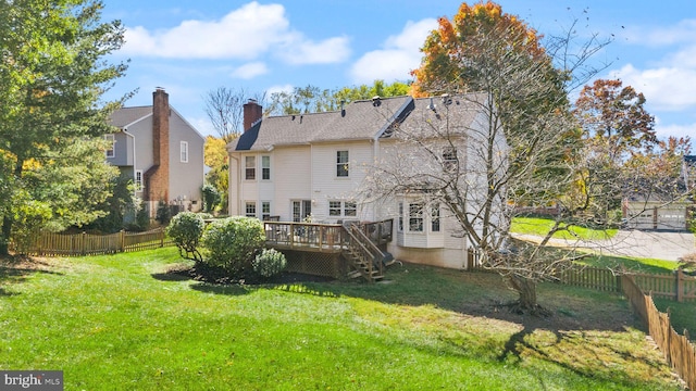 rear view of property with a wooden deck, a lawn, a fenced backyard, and a chimney