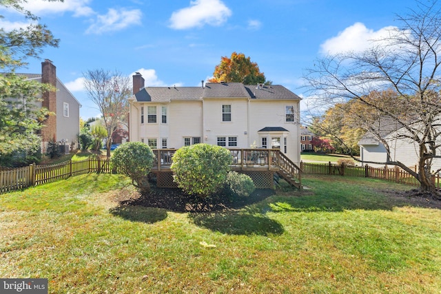 rear view of house featuring a fenced backyard, a lawn, a deck, and a chimney