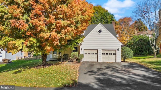 exterior space featuring a shingled roof, aphalt driveway, a lawn, a chimney, and a garage