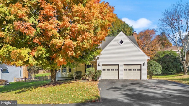 view of front of house with aphalt driveway, fence, a front yard, and a chimney