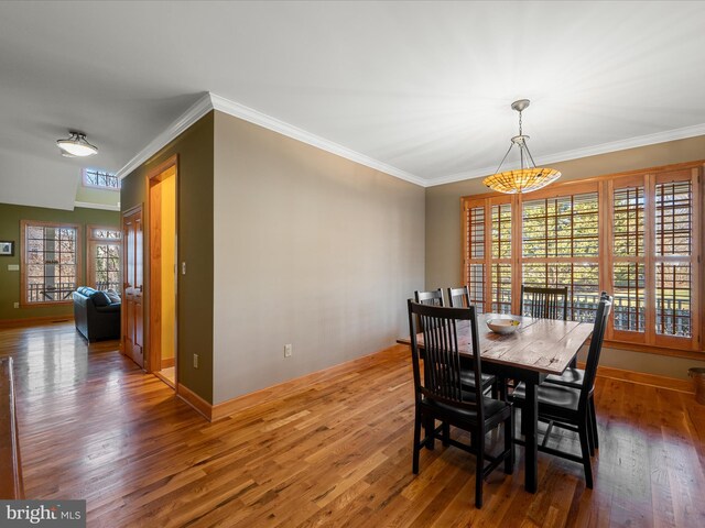 dining room featuring baseboards, wood finished floors, and ornamental molding