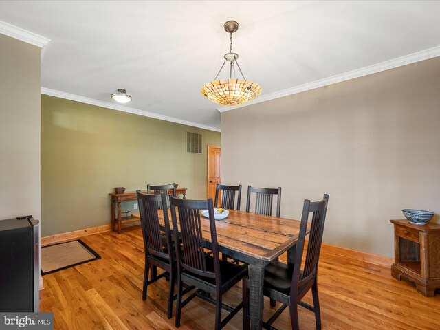 dining room with visible vents, light wood-style flooring, crown molding, and baseboards