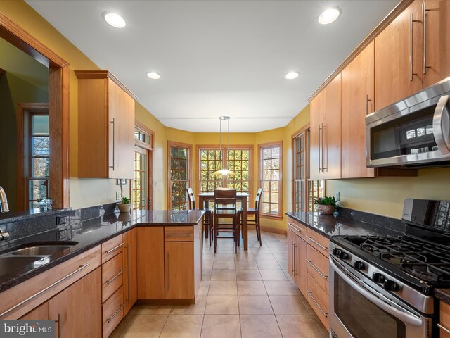 kitchen with a sink, dark stone counters, appliances with stainless steel finishes, and recessed lighting