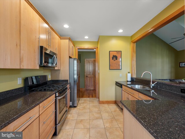 kitchen featuring a sink, dark stone countertops, light tile patterned floors, and stainless steel appliances