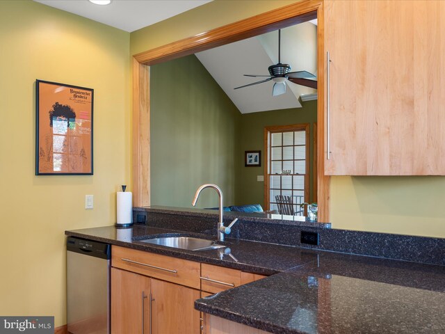 kitchen featuring dark stone counters, ceiling fan, a sink, vaulted ceiling, and stainless steel dishwasher