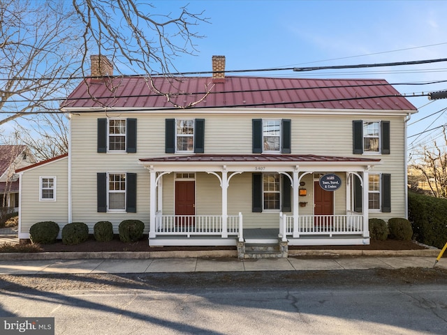 view of front facade featuring metal roof, a porch, and a chimney